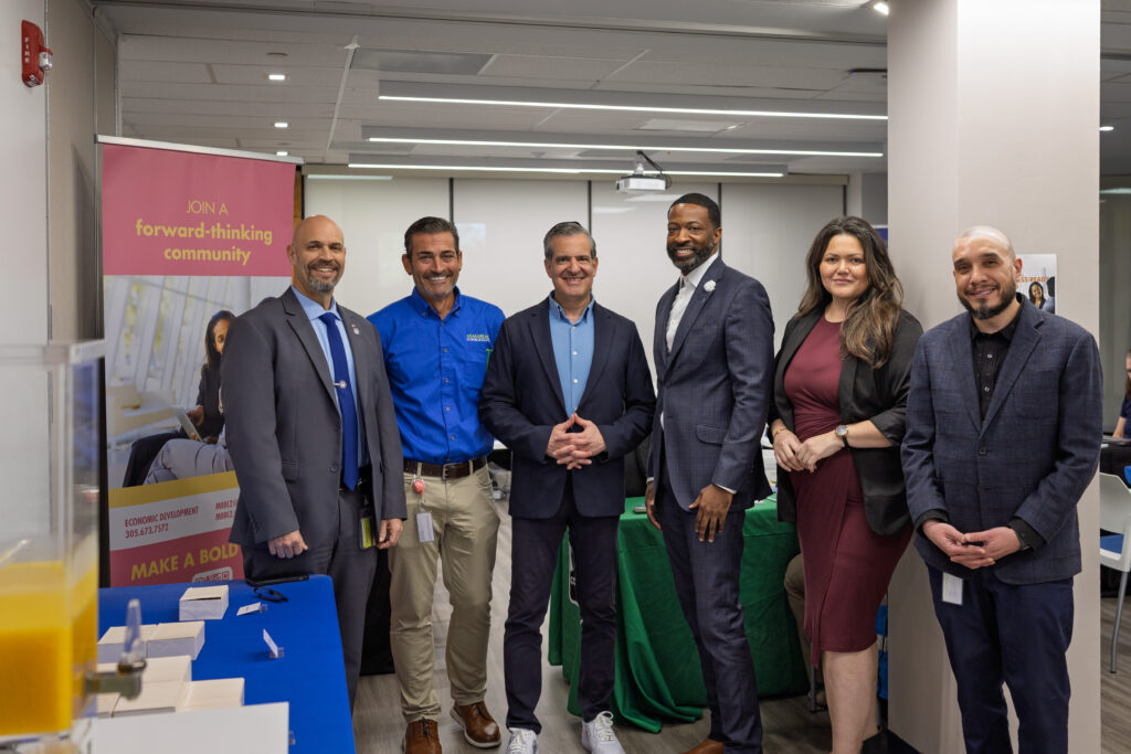 A group of Business Ready Day partners and staff stand together smiling in front of informational banners and resource tables.