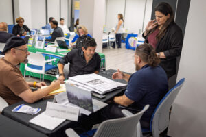 Several participants sit around a table covered with documents and binders while a Planning and Zoning staff member assists during Business Ready Day.