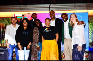 A group of event participants and speakers stand together smiling in front of the eMerge Americas event backdrop during "Celebrate"