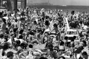 Historic photo of crowded Miami Beach shoreline during peak spring tourism, with visitors gathered closely along the beach.