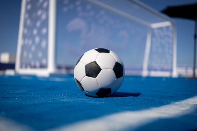 soccer ball with goal in background on blue playing surface