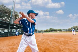 side angle picture of boy in baseball uniform at bat on baseball field