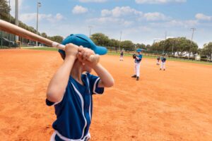 boy at bat on baseball field, opposing team can be seen in front of him