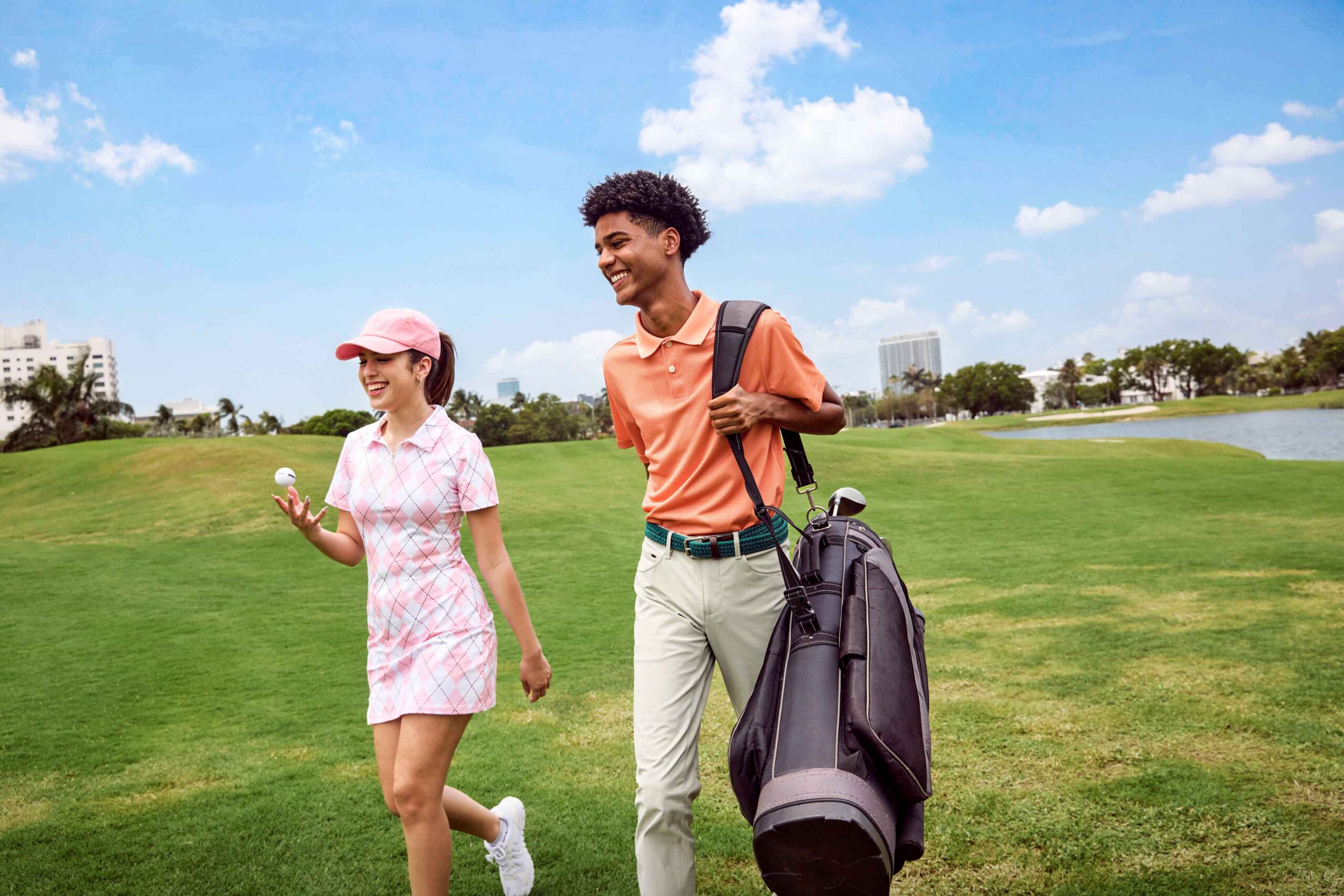 boy and girl in golf attire walking on grass with golf gear