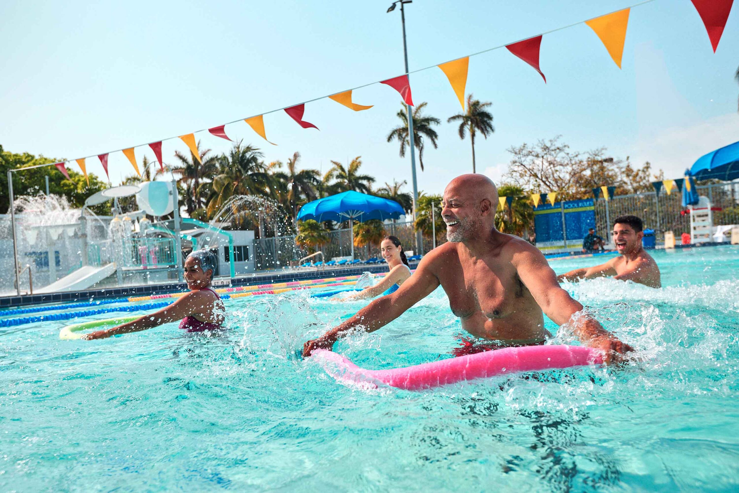 people doing group class in pool holding pool noodles