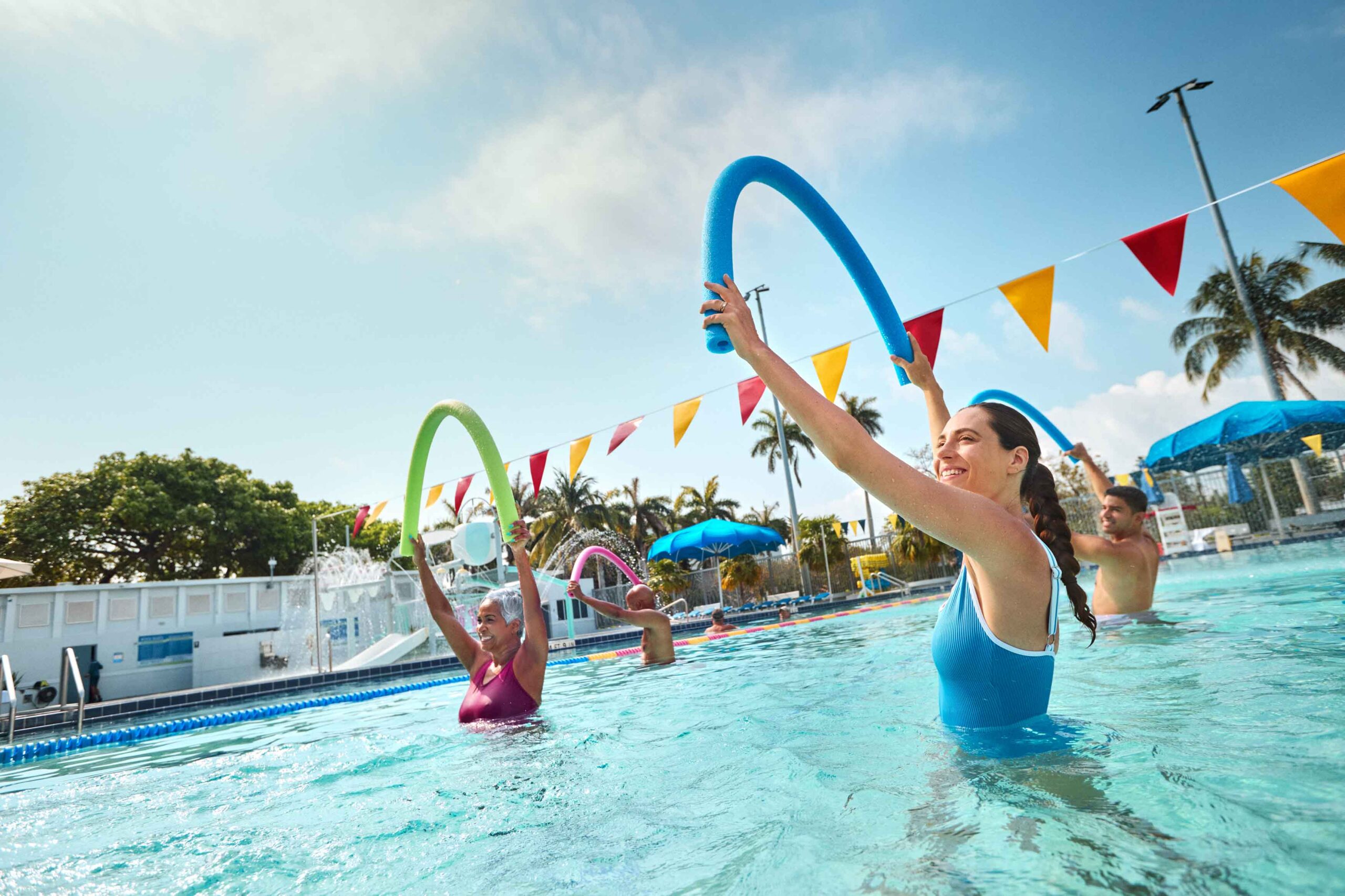 people doing group class in pool holding pool noodles