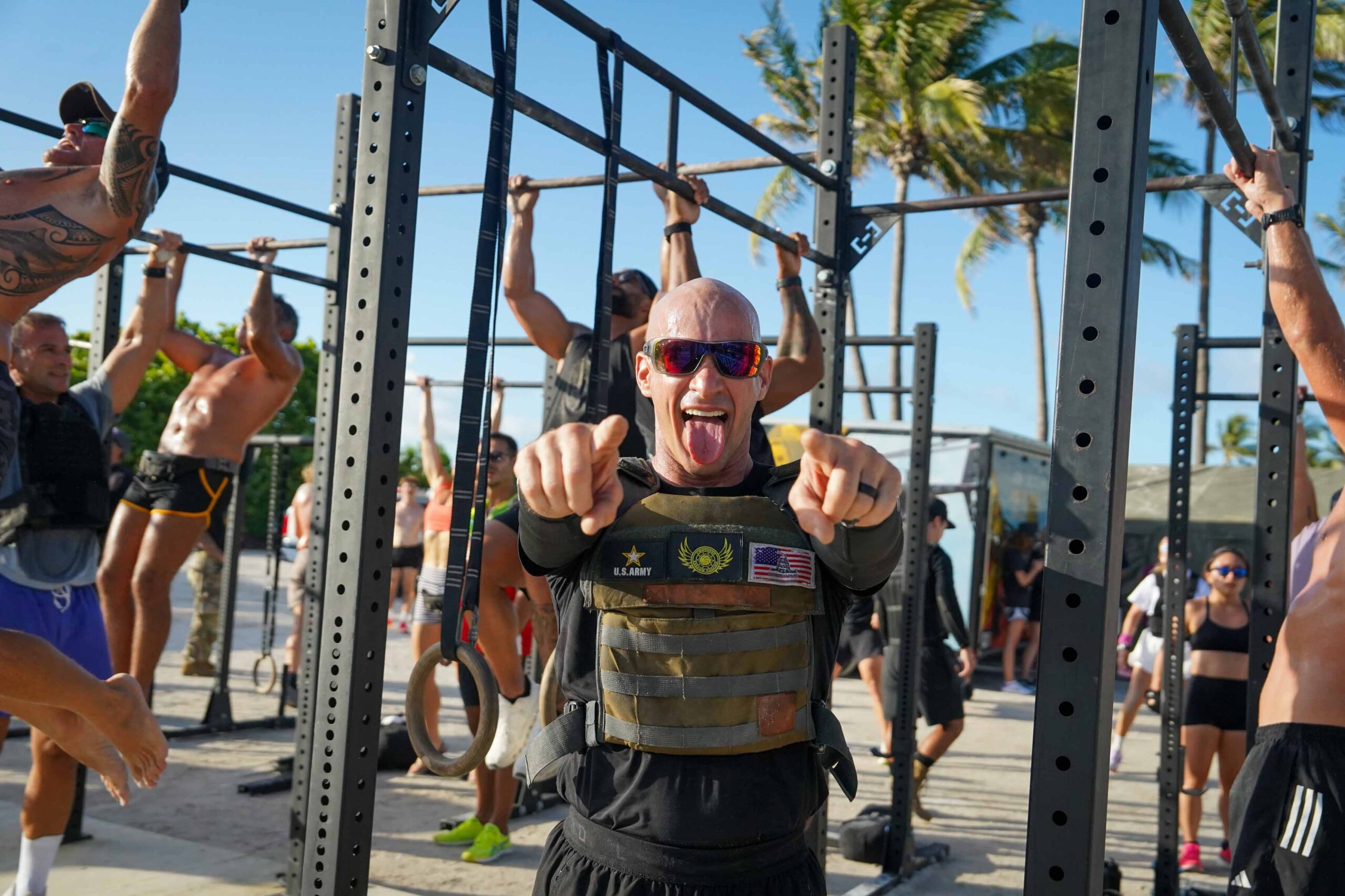 man with us army vest pointing while people work out in the background